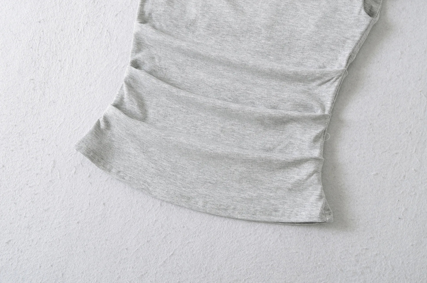 A shirt with a falling shoulder and shirring at the waist
