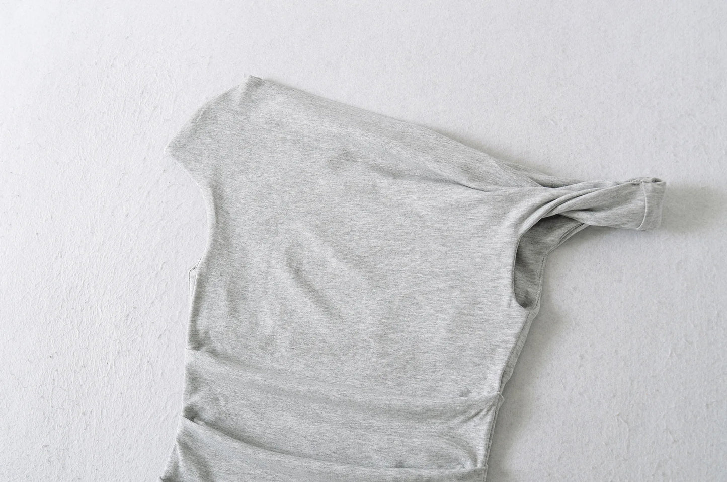 A shirt with a falling shoulder and shirring at the waist