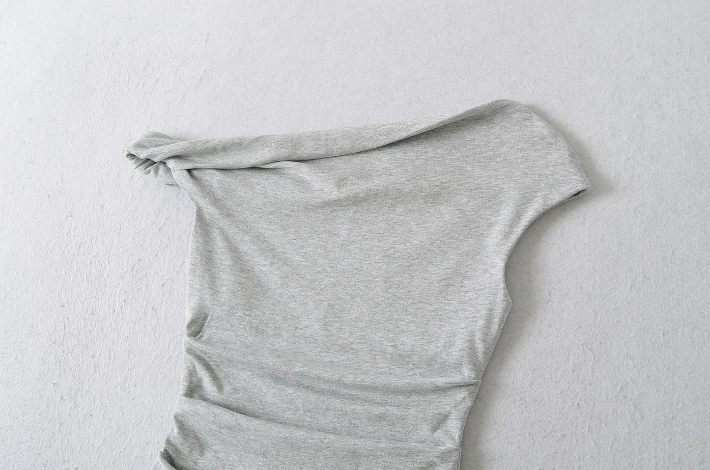 A shirt with a falling shoulder and shirring at the waist