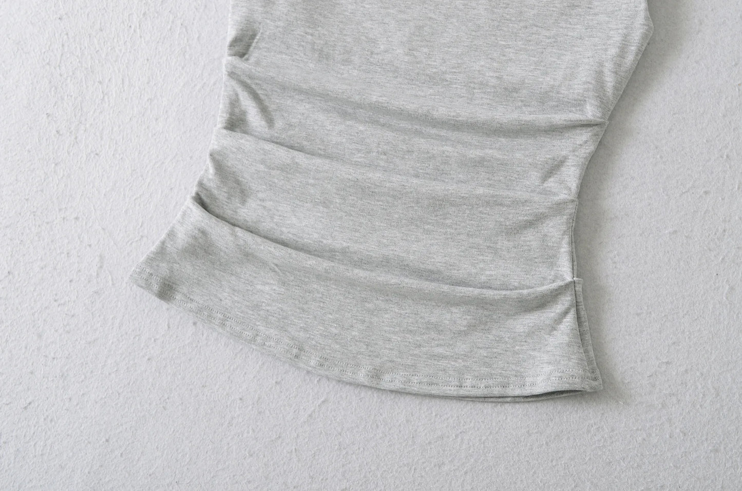A shirt with a falling shoulder and shirring at the waist